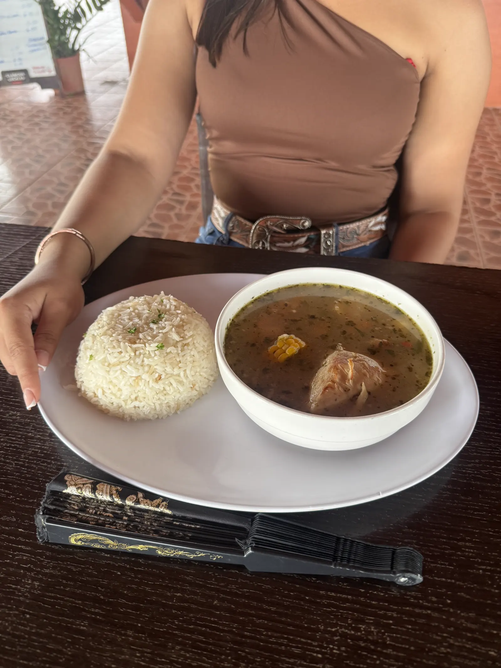 Plato de sopa y arroz sobre la mesa, con abanico decorativo en primer plano