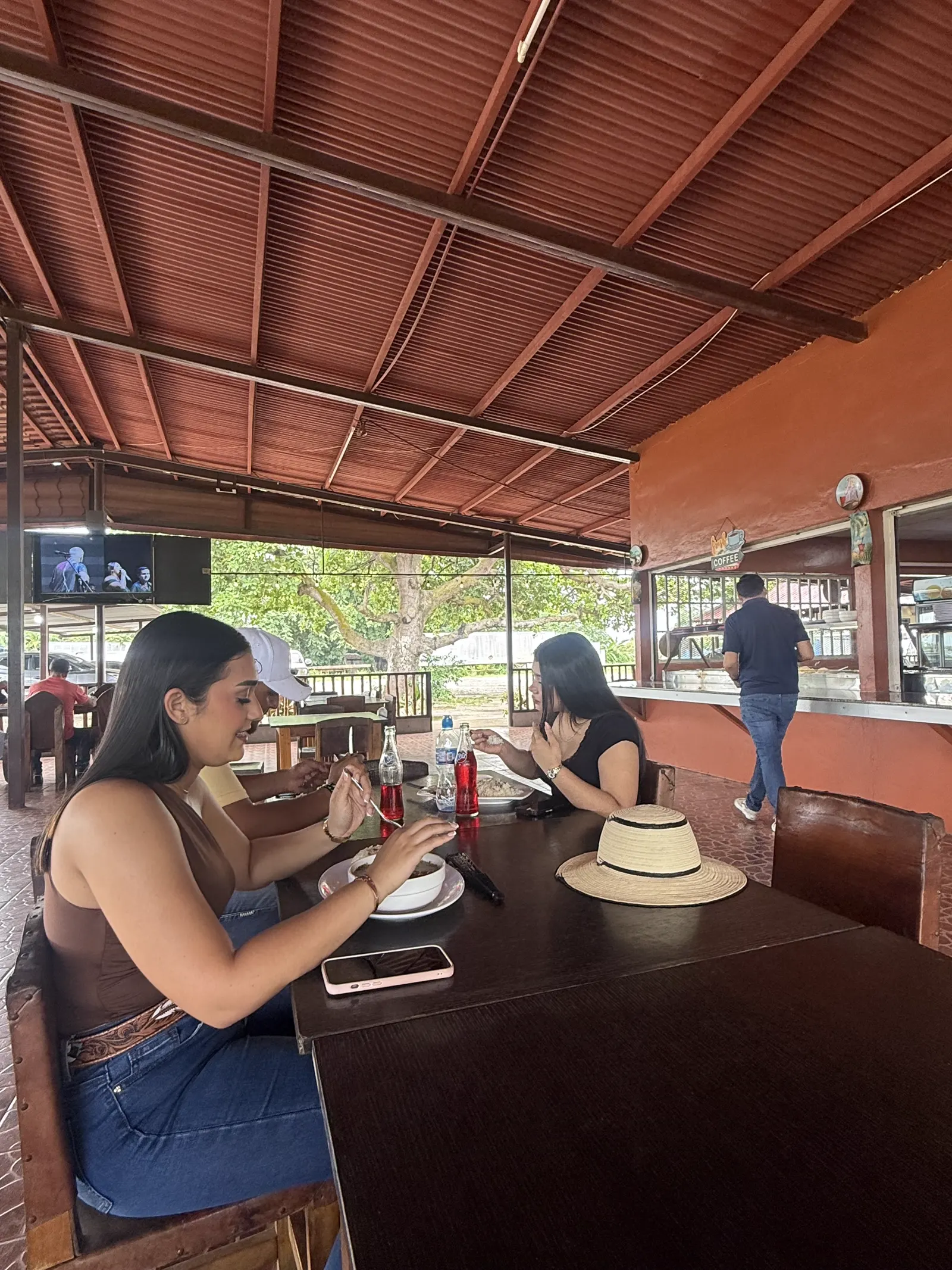Amigas comiendo en el rancho con una gaseosa, sombrero sobre la mesa