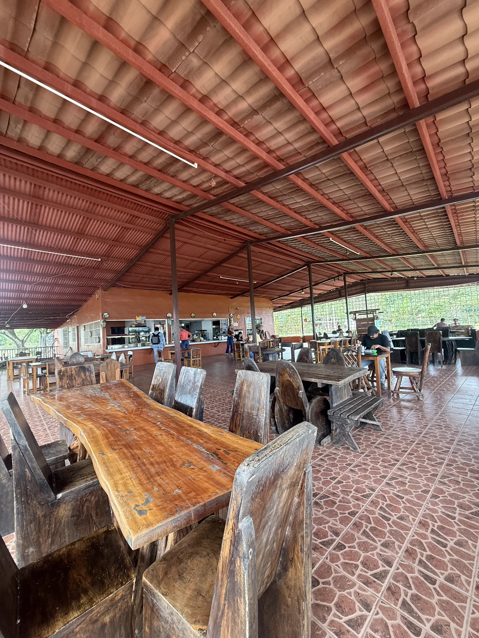 Mesa de madera maciza con canto natural en primer plano, comedor al fondo